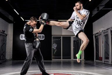 Two men practicing intense martial arts in a modern indoor gym. Action-packed training session.